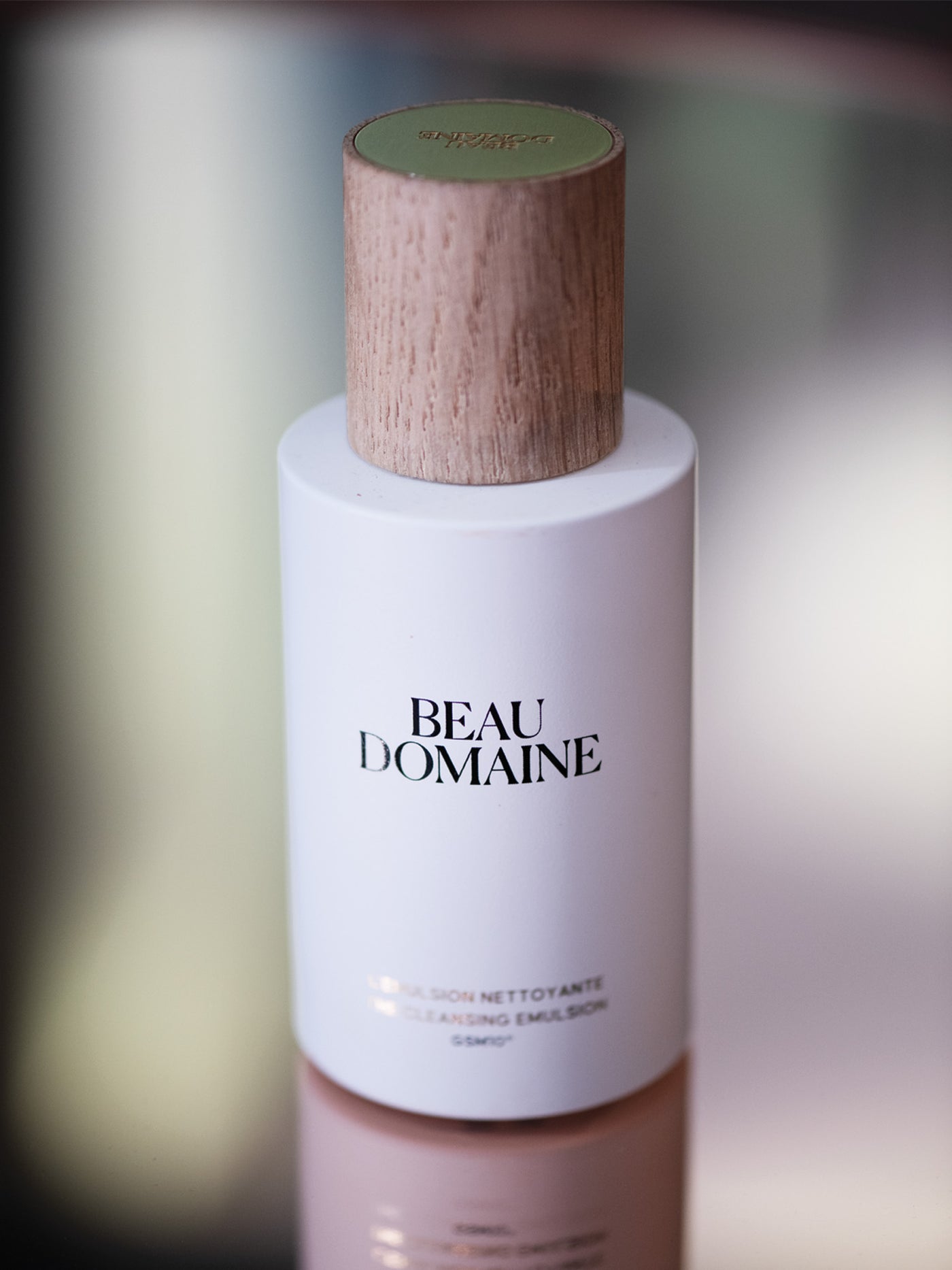 Beau Domaine hudpleje-flaske med træhætte på en sløret baggrund.