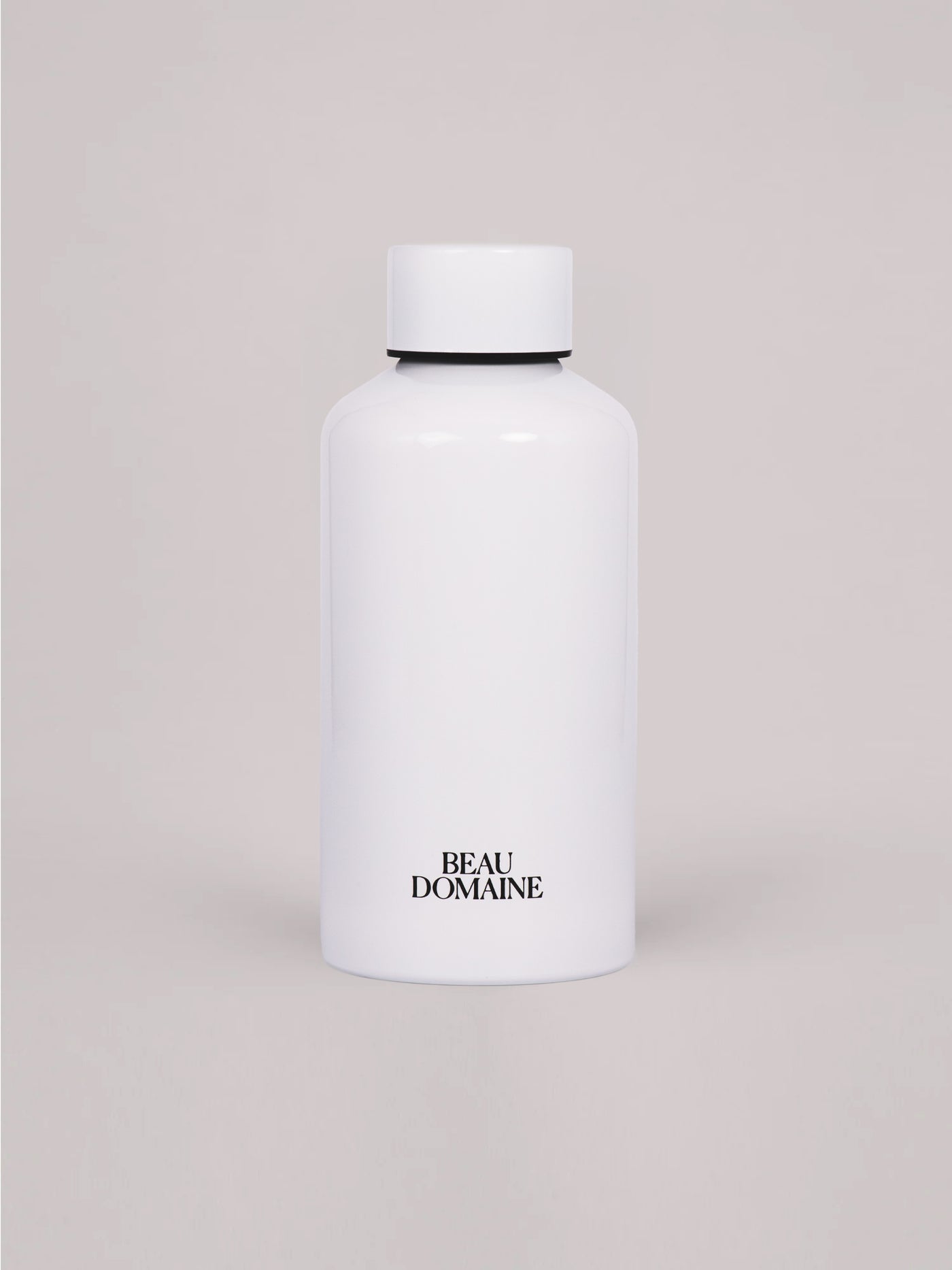 Hvid flaske med 'Beau Domaine'-branding på en beige baggrund
